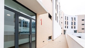 A modern building with a glass door entrance, numbered unit 1, and a clean, tiled floor. - Holi-Rent Pobladores (Camas)