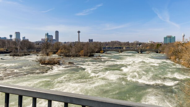 Une rivière avec un pont et, en arrière-plan, la silhouette d’une ville.