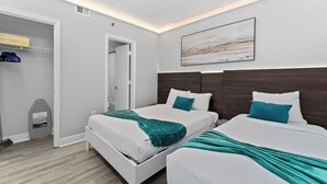 Ein modernes Hotelzimmer mit zwei Betten, einem begehbaren Kleiderschrank und einem großen abstrakten Gemälde an der Wand.