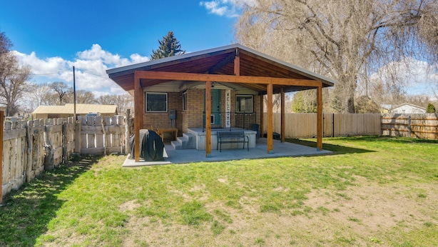 A covered patio with a wooden roof, a brick building, and a fenced yard. - Rexburg Escape w/ Fenced Yard + Covered Patio! (Rexburg)