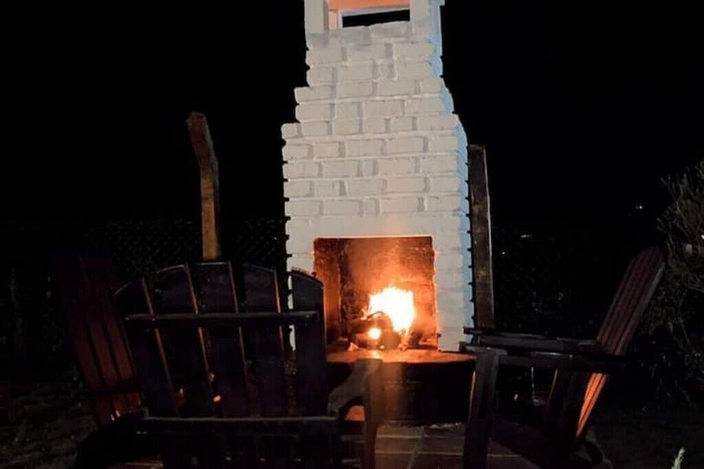 Ein Kamin aus Ziegelsteinen mit Feuer, umgeben von Sitzgelegenheiten im Freien.
