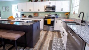 Una cucina moderna con mobili bianchi, elettrodomestici in acciaio inossidabile e un piano di lavoro in granito.