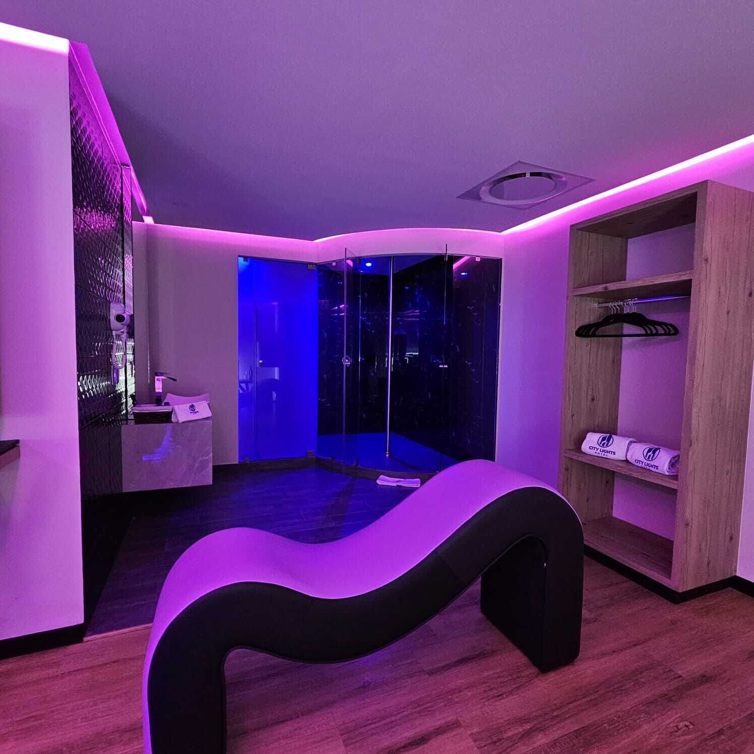 Una habitación moderna con un banco curvo, un panel de vidrio y un armario de madera con perchas.