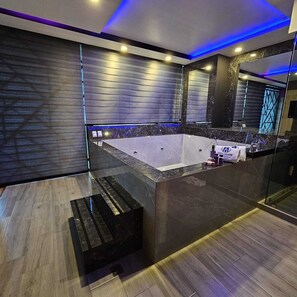 Une salle de bain moderne dotée d’une grande baignoire, d’une douche à parois de verre et d’un comptoir en marbre.