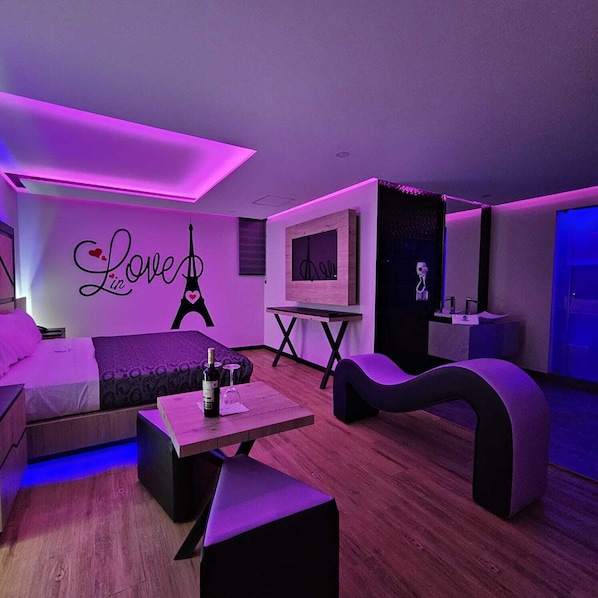 Un dormitorio moderno con una cama, un escritorio y una silla. Se observa una pared con un cartel que dice 'Love' y un marco de fotos.