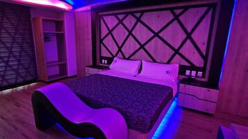 A modern bedroom with a wooden headboard, a patterned bedspread, and a bench.