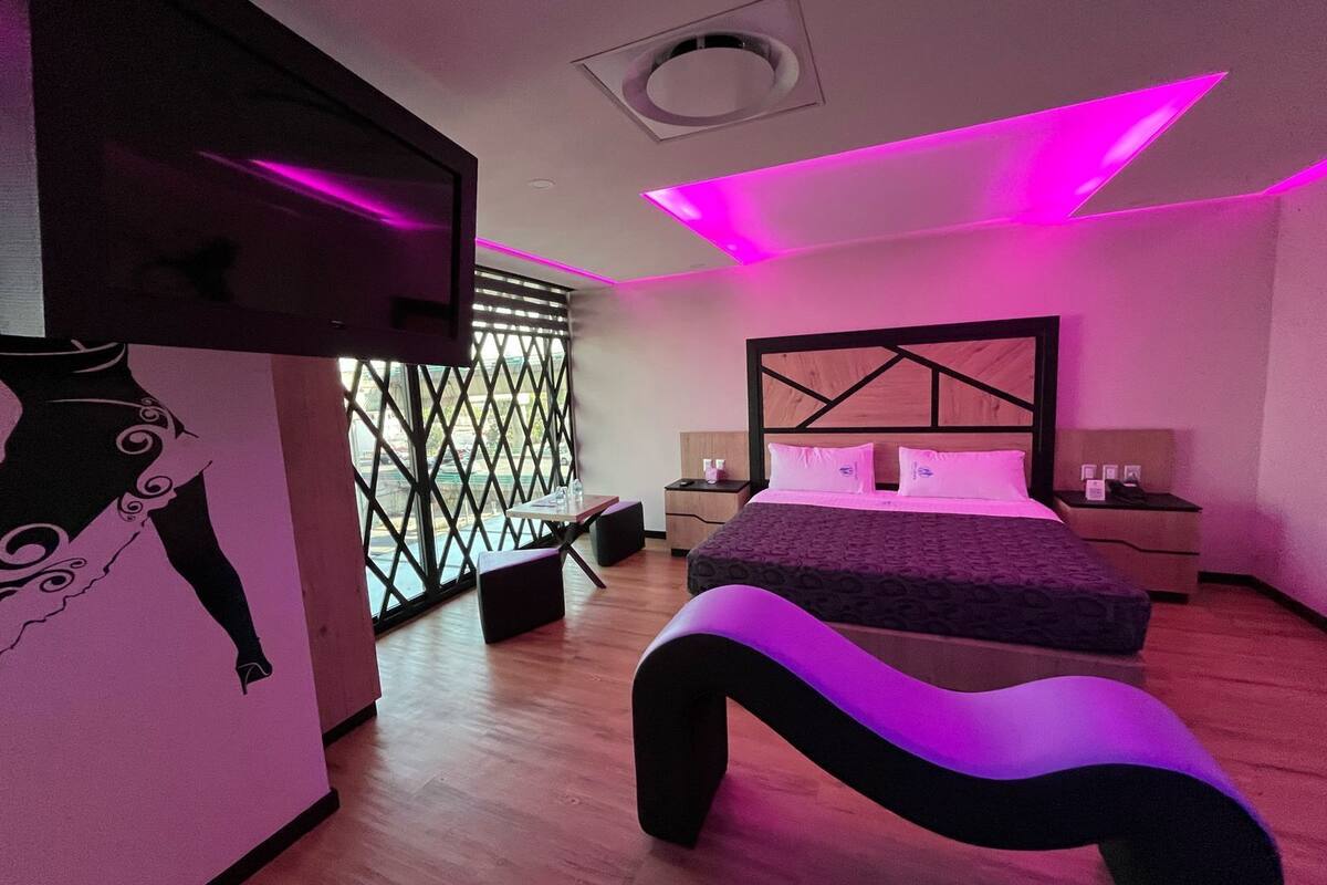 Une chambre à coucher moderne avec un lit, des tables de chevet, un bureau et une chaise.