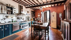 A kitchen with wooden beams, a dining table with chairs, and a refrigerator.