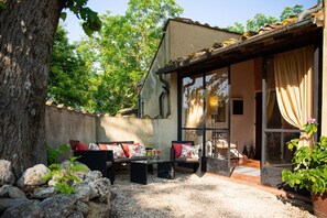 Eine Terrassenfläche mit Sitzgelegenheiten, einer Pergola und Blick auf den Garten.
