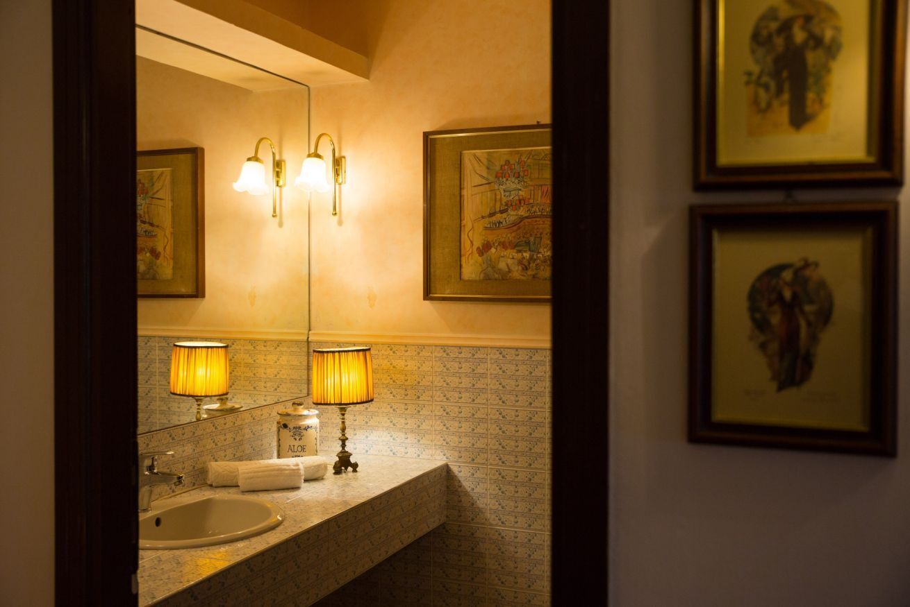 A bathroom with a sink, two lamps, and framed artwork on the wall.
