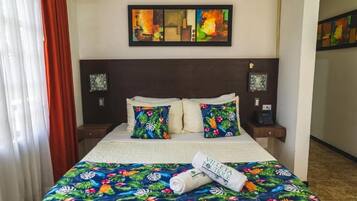 A hotel room with a bed, two pillows, a nightstand, a phone, and a wall art piece.