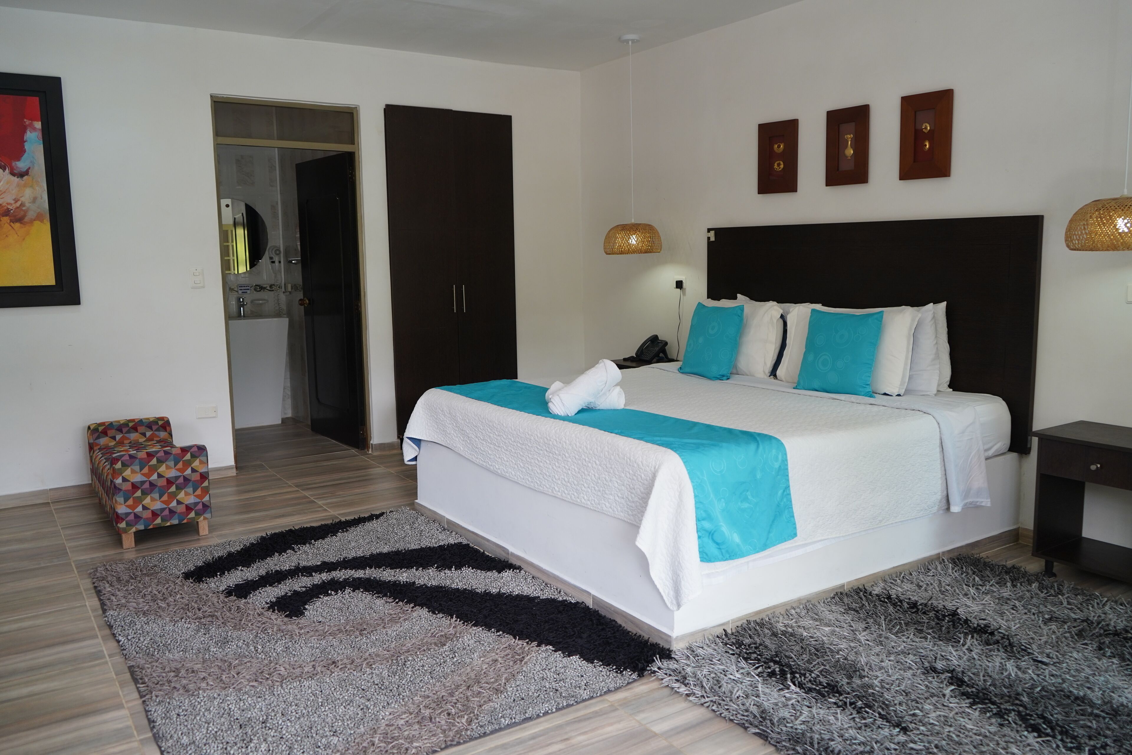 Un dormitorio moderno con una cama grande, una mesita de noche pequeña, una mesita auxiliar y una puerta que da a un baño.
