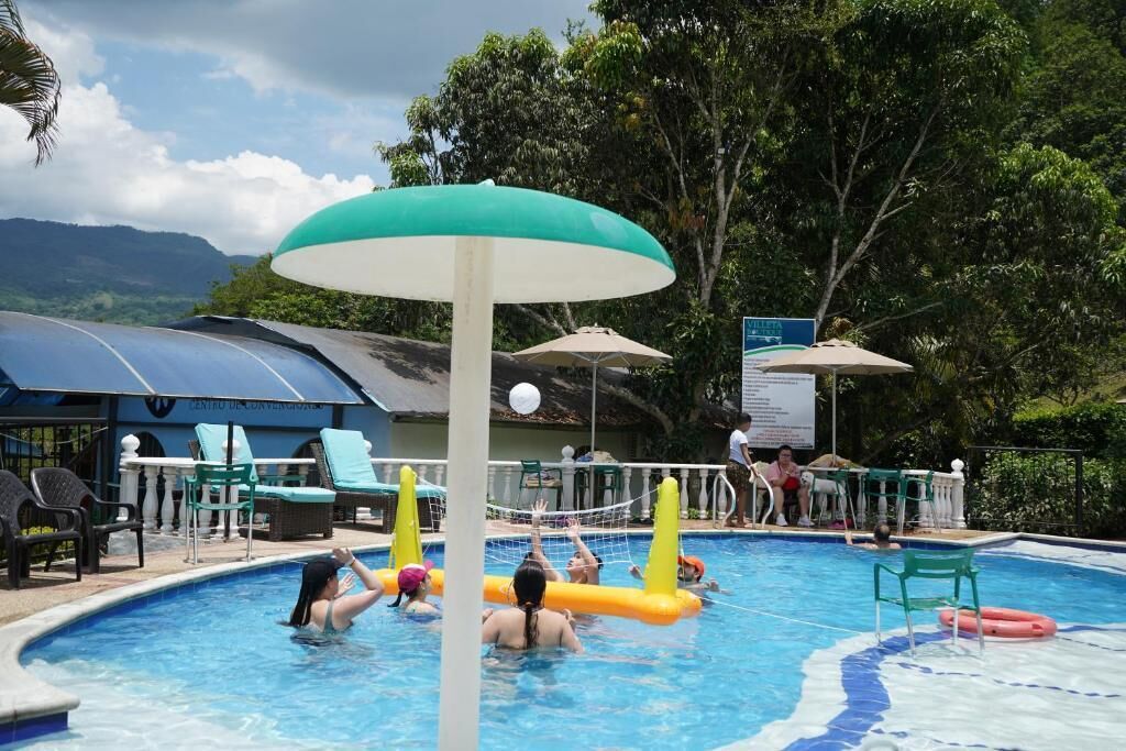 A swimming pool with inflatable barriers, lounge chairs, and umbrellas.