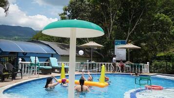 A swimming pool with inflatable barriers, lounge chairs, and umbrellas.