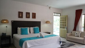 A bedroom with a large bed, bedside tables, a sofa, and a view of the outdoors.