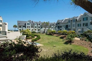 A modern hotel with multiple-story buildings, a well-maintained lawn, and a clear view of the ocean.