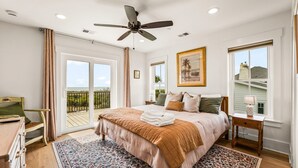 Ein Schlafzimmer mit Bett, Deckenventilator, Fenster mit Aussicht, Nachttisch und Stuhl.