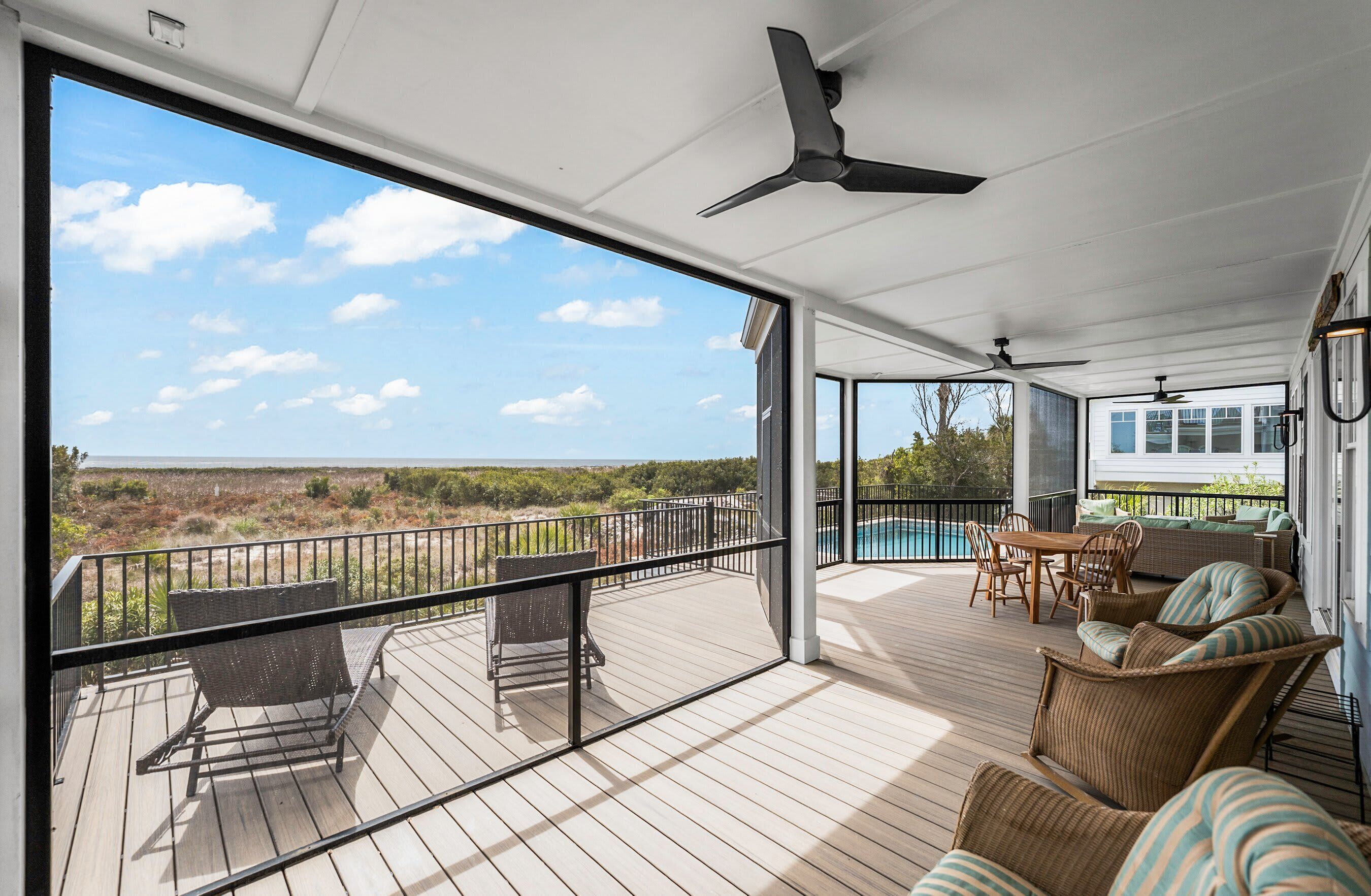 A covered outdoor area with a pool, wicker furniture, and a view of the landscape.