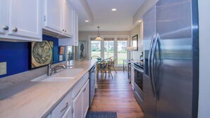 A modern kitchen with a stainless steel refrigerator, white cabinets, and a wooden floor.