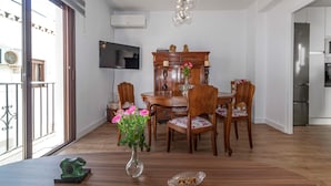 A dining area with a wooden table and chairs, a vase with flowers, and a modern chandelier. - Beach front apartment in Nerja with WiFi (Nerja)