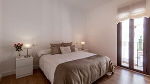 A bedroom with a large bed, two bedside tables with lamps, a window with curtains, and a view of the outside. - Beach front apartment in Nerja with WiFi (Nerja)
