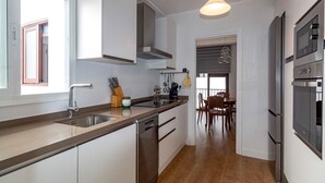 A modern kitchen with a large island, stainless steel appliances, and a dining area with a table and chairs. - Beach front apartment in Nerja with WiFi (Nerja)