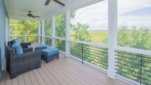 A covered outdoor area with wicker furniture, ceiling fans, and a view of greenery. - 104 Davis Love Drive (Fripp Island)