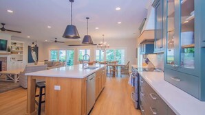 A modern kitchen with a central island, pendant lighting, and a dining area with a view of the outdoors. - 104 Davis Love Drive (Fripp Island)