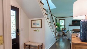 A hallway with a wooden bench, a staircase, a framed picture, and a television on the wall. - 18 Veranda Beach Drive (Fripp Island)