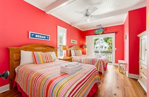 Une chambre d’hôtel avec deux lits, un ventilateur de plafond et une vue sur l’extérieur.