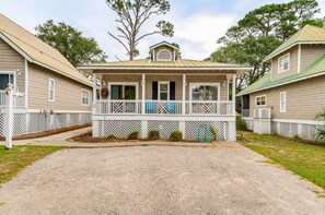 A two-story house with a porch, white picket fence, and a gravel driveway.