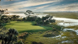 A golf course with a water body in the background, surrounded by trees and vegetation. - 622 Newhaven (Fripp Island)