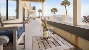 A wooden table with a bottle and glasses, overlooking a balcony with a view of the sea and palm trees. - 622 Newhaven (Fripp Island)