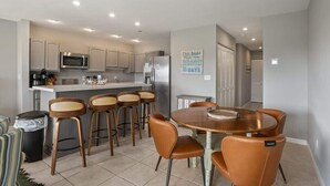 A modern kitchen with a dining area, including a round table and bar stools.