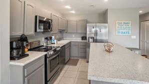 A modern kitchen with stainless steel appliances, a granite countertop, and a sign on the wall.
