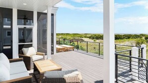 A covered outdoor area with wicker furniture, a table, and a view of the landscape. - 718 Swordfish Road (Fripp Island)