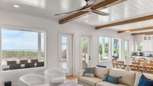 A spacious living room with a large window, a ceiling fan, and a view of the outdoors. - 718 Swordfish Road (Fripp Island)