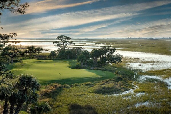 A golf course with a water body in the background, surrounded by trees and vegetation. - 657 Newhaven (Saint Helena Island)