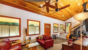 A cozy living room with leather sofas, a wooden ceiling, and a fireplace.