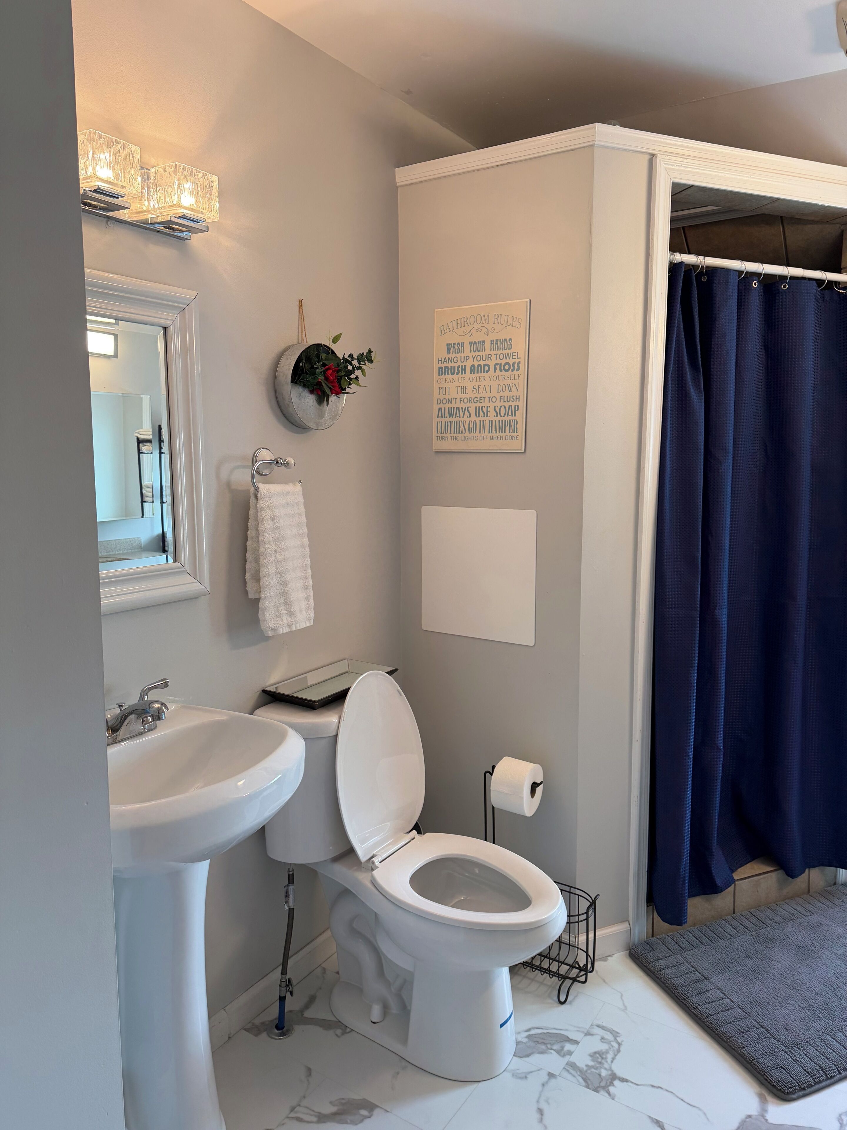 Un baño con lavamanos, inodoro y cortina de ducha.