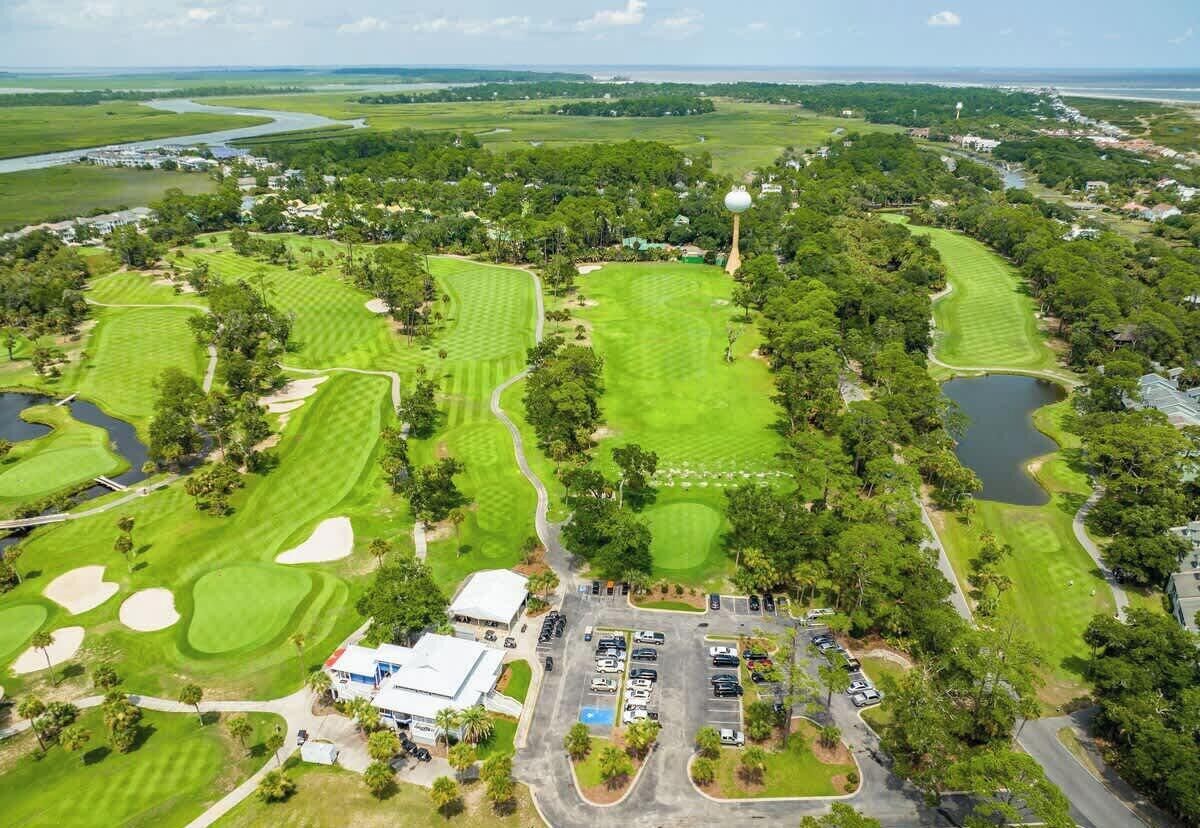 An aerial view of a golf course with multiple greens, sand bunkers, and a clubhouse.