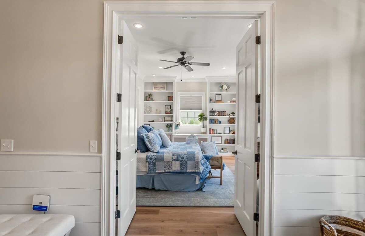 A bedroom with a bed, a ceiling fan, a bedside table, and a nightstand.