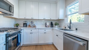 Eine moderne Küche mit weißen Schränken, Edelstahlgeräten und Holzboden.