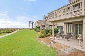 A residential building with a patio area, outdoor seating, and a well-maintained lawn.
