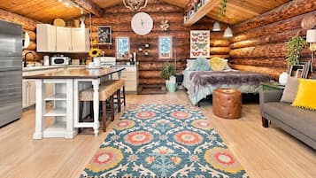L’intérieur d’une cabane en rondins comprend une cuisine, un coin repas et une chambre confortable avec un lit et un espace salon.