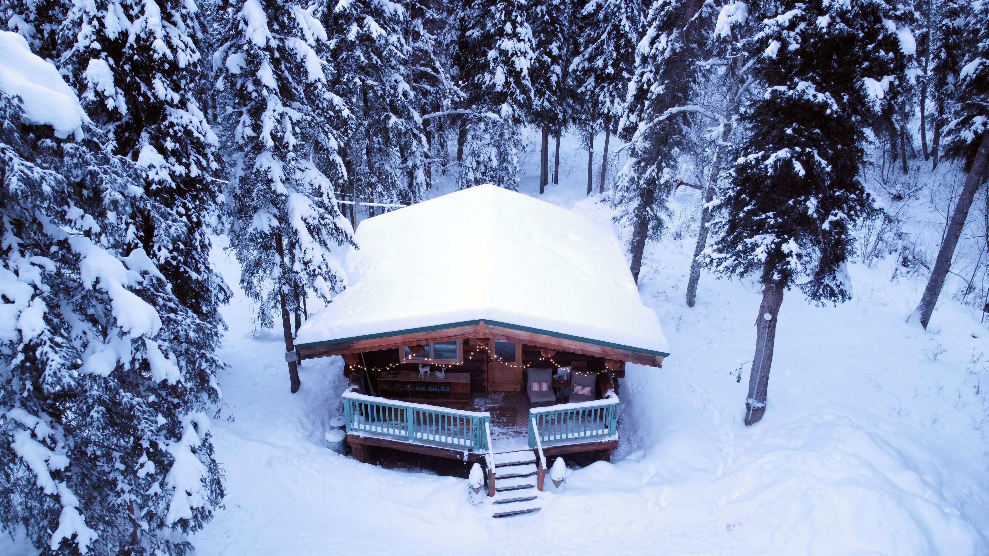 Una cabaña con techo nevado, rodeada de árboles.