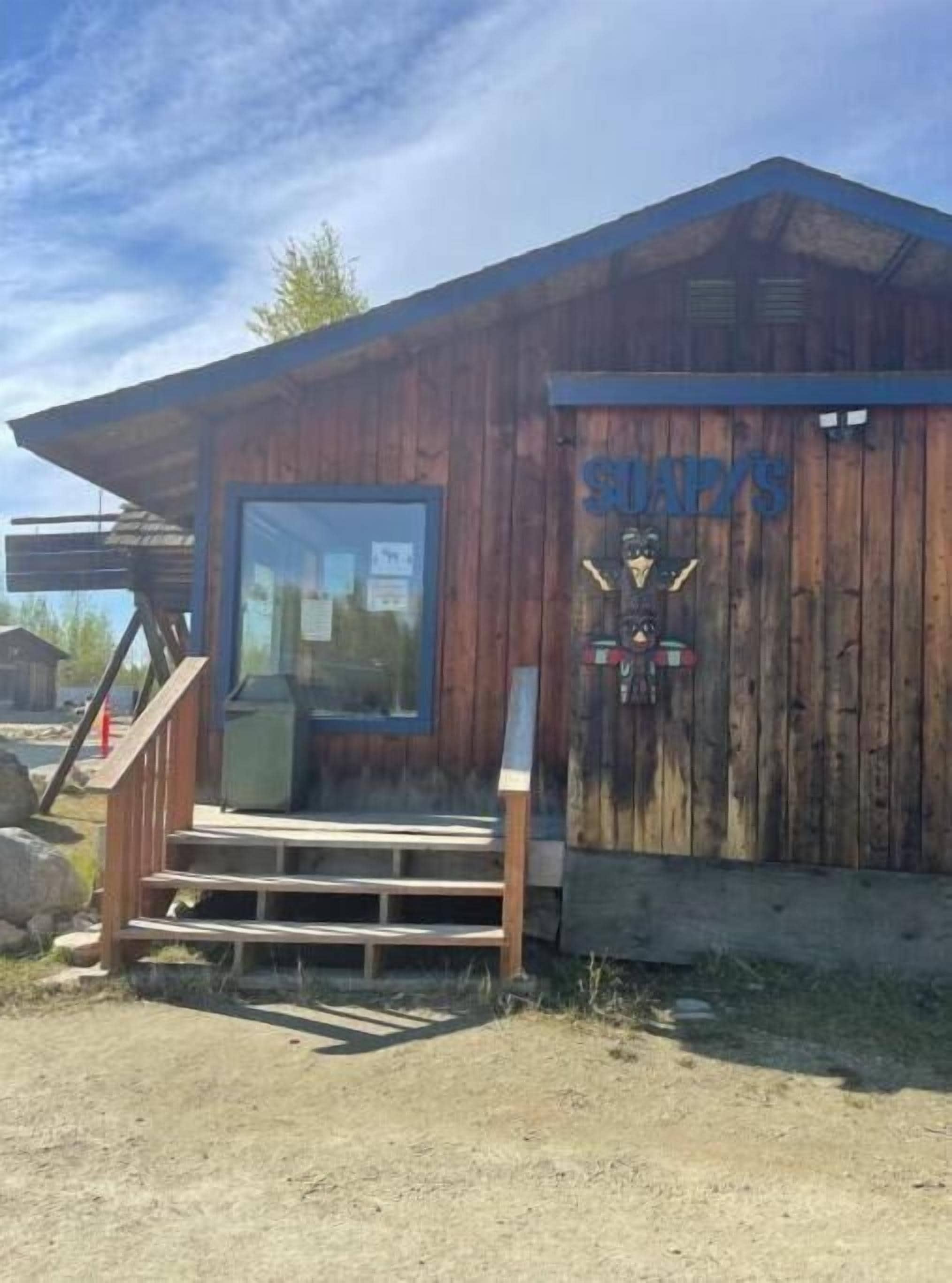 Un edificio de madera con un letrero que dice "SUMPYS" y una escalera que lleva a una puerta.