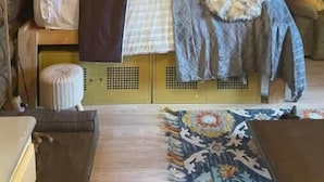 Acogedora habitación tipo cabaña de madera con una cama, una mesita y una estantería.