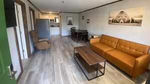 A living room with a sofa, a coffee table, a TV, and a dining area with chairs and a table. - 2BD 2BA w/Kitchenette close to Silver Dollar City (Branson)