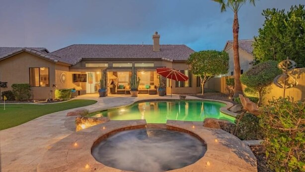 Ein modernes Haus mit Swimmingpool, Whirlpool und einer Terrassenanlage mit Gartenmöbeln.
